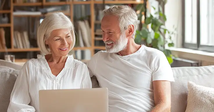 Älteres Paar mit Laptop auf Sofa